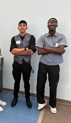 Two staff standing against wall
