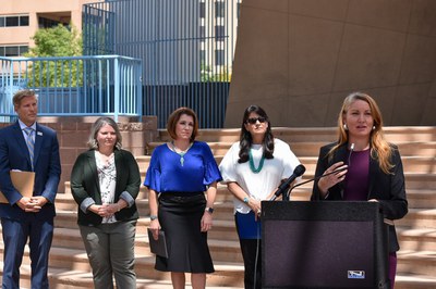 Congresswoman Melanie Stansbury speaking at a podium with Mayor Tim Keller, Councilor Tammy Fiebelkorn, Councilor Brook Bassan, and  Councilor Renée Grout behind her.