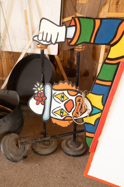 A clown cutout laying sideways in front of some lamps.