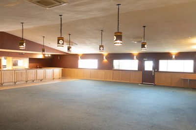 A large open room with hanging lights and a bar.