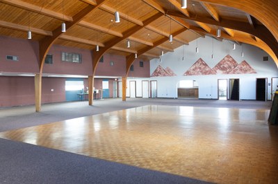 A dance floor next to carpeted areas with exits on 2 walls.