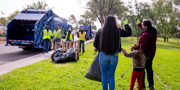 A family waiving at City of Albuquerque Solid Waste Department employees