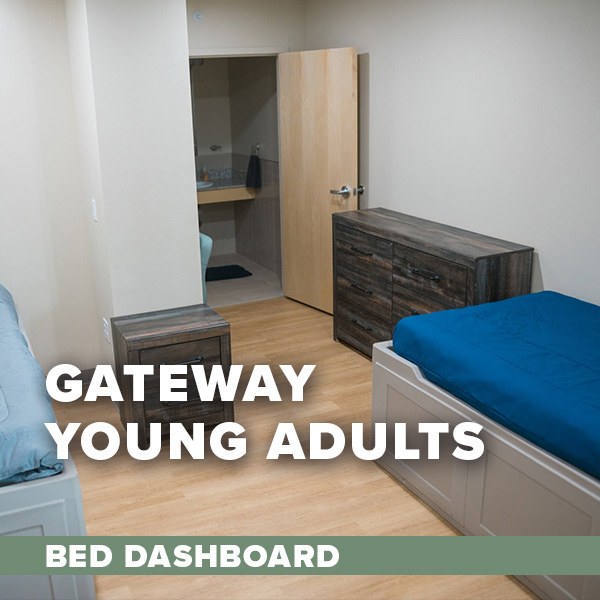A single bed with blue sheets and two dark wooden dressers and an open door at the end of the room leading into a bathroom. Text overlay: Gateway Young Adult Bed Dashboard.
