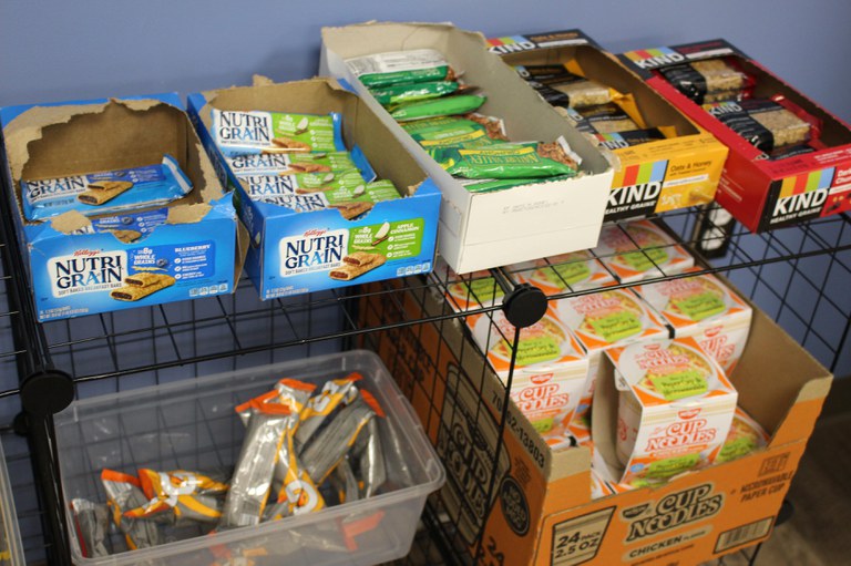 A wire cabinet with ramen, Nutri Grain bars, and other snacks