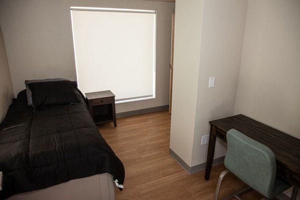 A bedroom at the Young Adult Shelter with a window,  bed and desk.