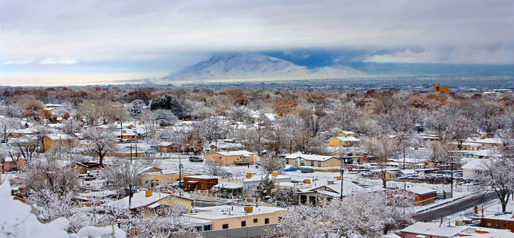 Winter in Albuquerque Snow covered houses and trees with the Sandia Mountains in the background.