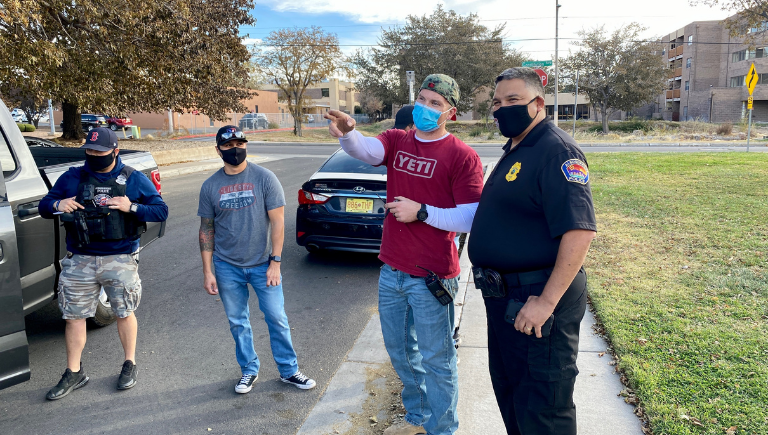 Three APD officers talking with APD Chief Harold Medina near a park.