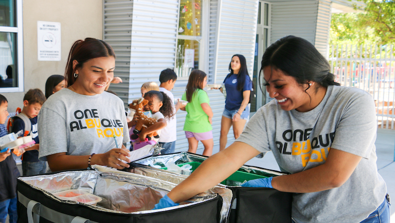 Two young women serving meals to children.