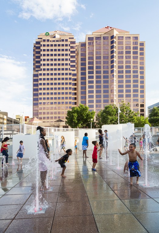 A group of children and adults playing on a splashpad on Civic Plaza. 