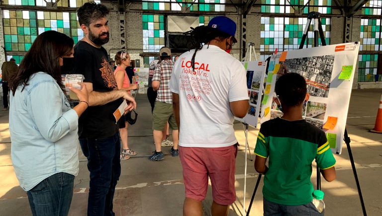 A parent and child, and a couple looking at Rail Trail plans at an event at the Rail Yards.