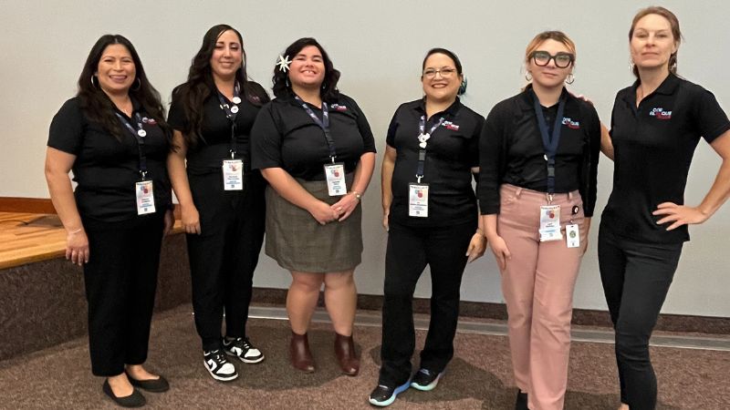The five person Civic Engagement Team posing for a picture with hot air balloons in the background.
