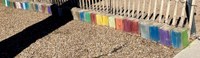 Fairwest Color Block painted artwork of multi-colored concrete block arranged along a fence.