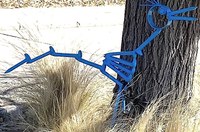 A stylized, cut-out style blue metal artwork sculpture of a roadrunner in profile.
