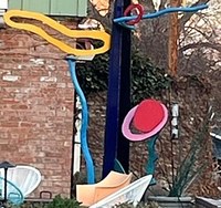 A modern metal artwork sculpture featuring various pieces in multiple colors creating lines and loop shapes of multiple lengths and fidelity.