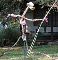 A modern artwork sculpture of a danging figure holding a stick.