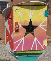 A painted, postbox-style object with a cut five-point star design in the front and painted with pink, orange, and yellow in a gradient from top to bottom.