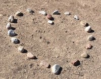 Rocks arranged into the shape of a heart on the dirt.