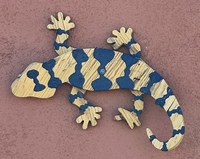 A sculpture of a blue and beige lizard mounted to a wall.