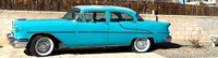 A classic car with turquoise paint parked on the side of a street.