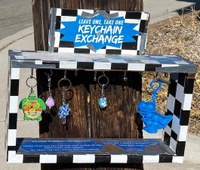 A small open-sided box frame with keychains dangling from hoops within mounted to a telephone pole.