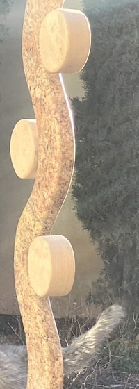 A modern stone artwork of a flowing line with circles in ever "dip" of the line, alternating as it goes up.
