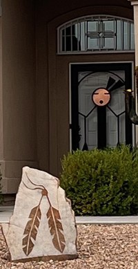Two brown feather reliefs on a light tan stone in a front yard.