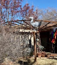 A metal duck sculpture attached to the top of a wooden pole.