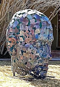 A large metal sculpture made from sheets of metal assembled to resemble a human head.