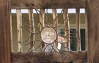 A metal sculpture of a stylized sun with a face and large rays.
