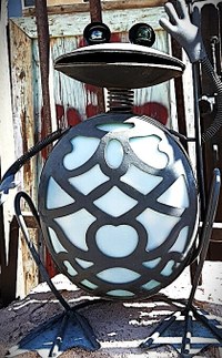A metal art sculpture of a stylized frog seated.