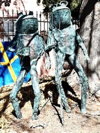 A metal art sculpture of pair of stylized frogs.