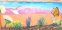 A wall art mural of a desert landscape with a butterfly and flowers.