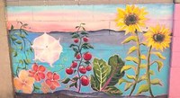 A wall art mural of a desert landscape with flowers, mountains and a blue sky.
