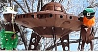 A metal sculpture of a space ship and two aliens.