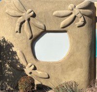 Dragonfly relief sculptures on an adobe wall.