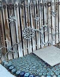 Various pieces of small metal artworks attached to a wood fence.