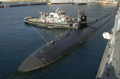 A dockside view of the submarine USS Albuquerque and a tugboat.