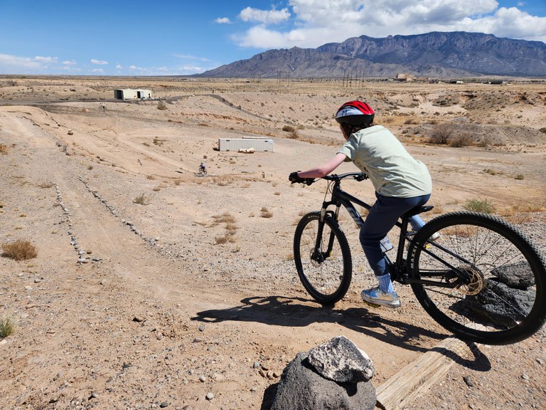 A middle school student rides a mountain bike at a bike park outdoors.