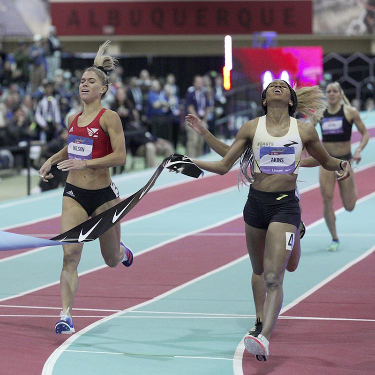 Two women finish a race on the indoor track