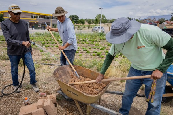 Loma Linda Community Garden Horno Three people creating an adobe clay mixture for a new horno at the community garden.