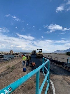 A path being paved by heavy machinery and construction workers.