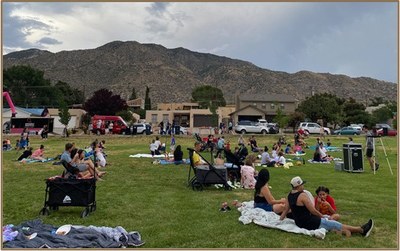 People sitting and lounging on the grass at a City park.
