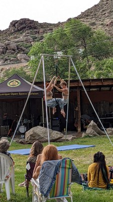 Two performance artists dressed like fish perform acrobatics on a hanging rig.