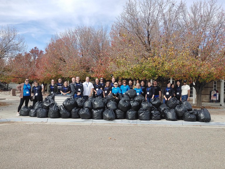 Group photo of Terrapin Hospitality volunteers outdoors next to a curb with a stack of organized trash bags.