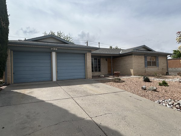 A single story brick home with two blue garage doors.