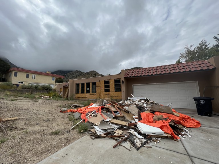 A dilapidated house with a scrap pile in the front yard.