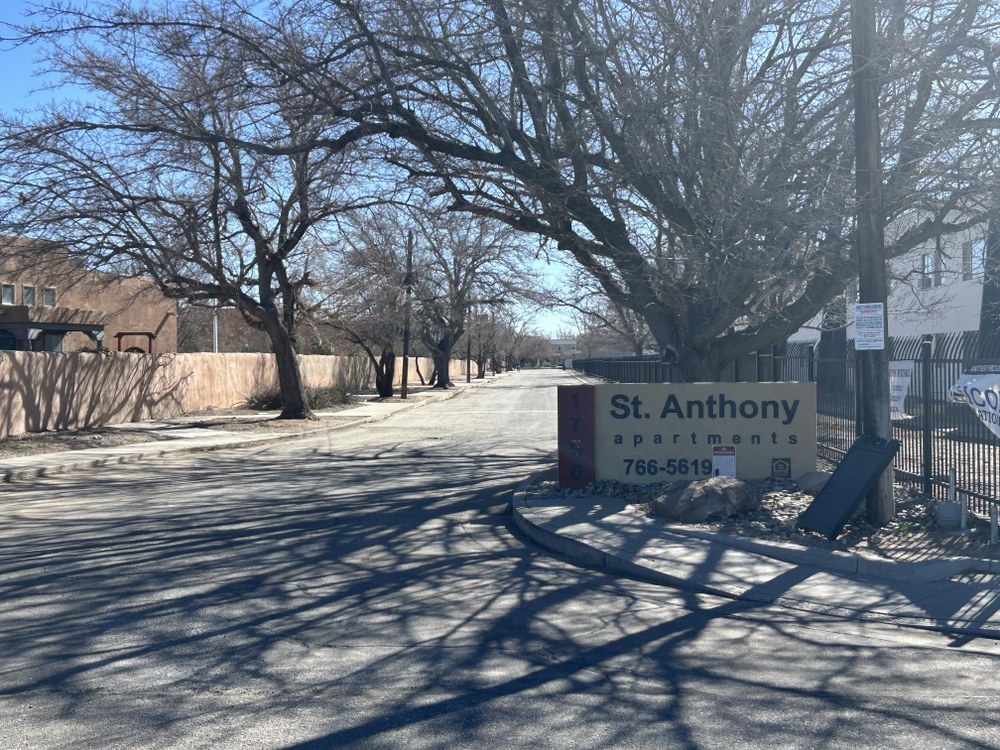 1750 Indian School Rd NW A driveway that leads into an apartment complex with a sign along the fence that reads, " St. Anthony Apartments".