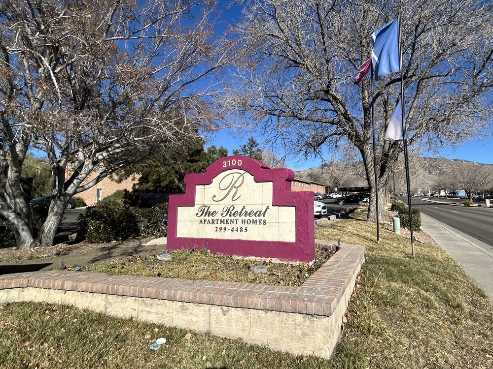 3100 Jane Pl NE A red and white sign that reads, "The Retreat Apartment Homes" mounted in the grass in front of a large apartment complex.