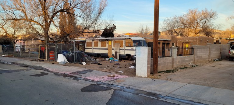 A dilapidated house with an RV in the front yard.