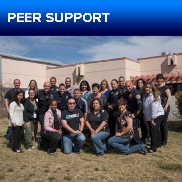 A jpg of the button for the Peer Support section, featuring a group of officers in uniform and plain clothes on kneeling and standing on grass in front of a building.